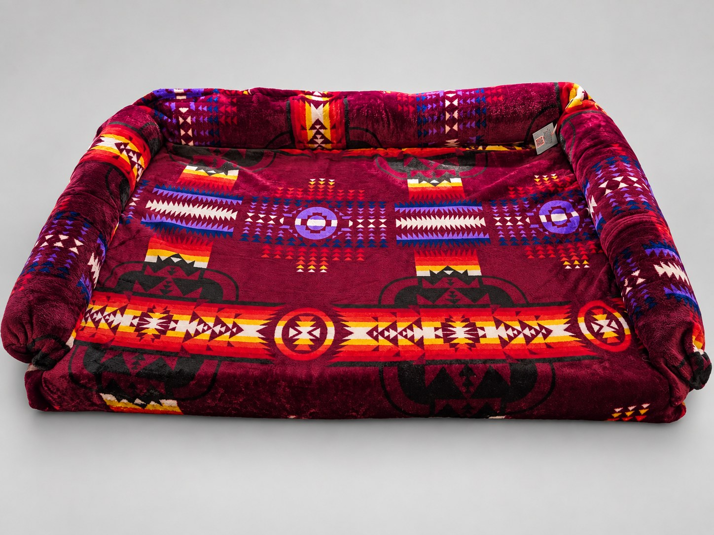 Large Bolstered Imitah bed with burgundy geometric fabric and raised back and side bolsters