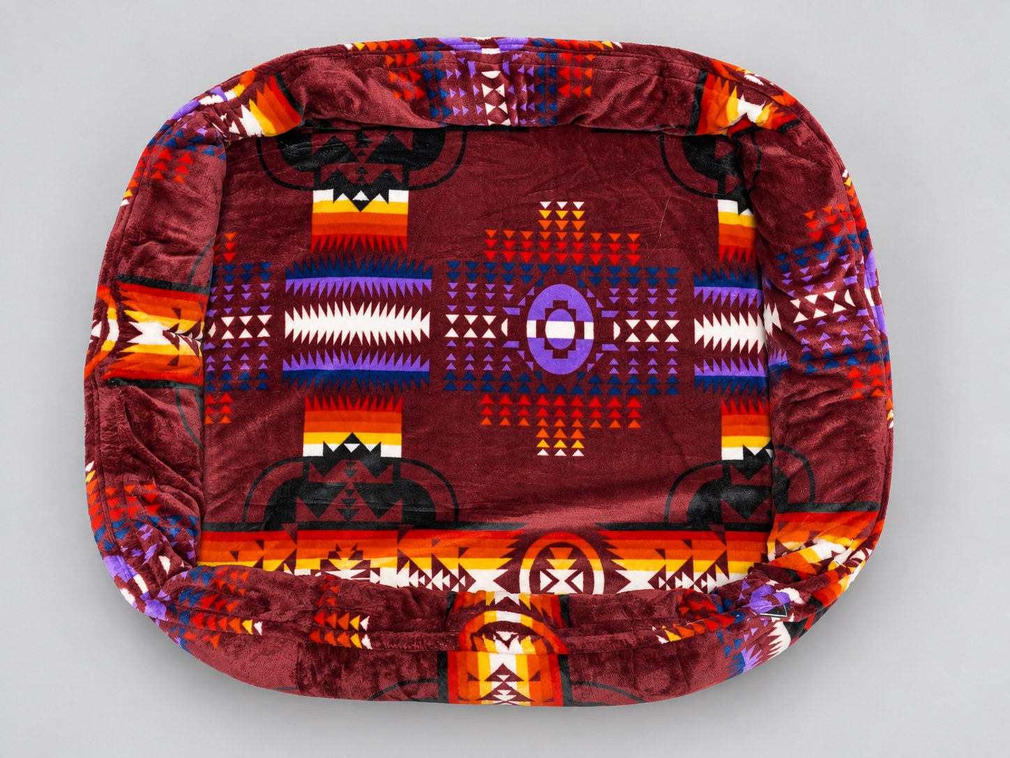 Medium Donut Imitah bed with burgundy geometric fabric and a continuous padded rim